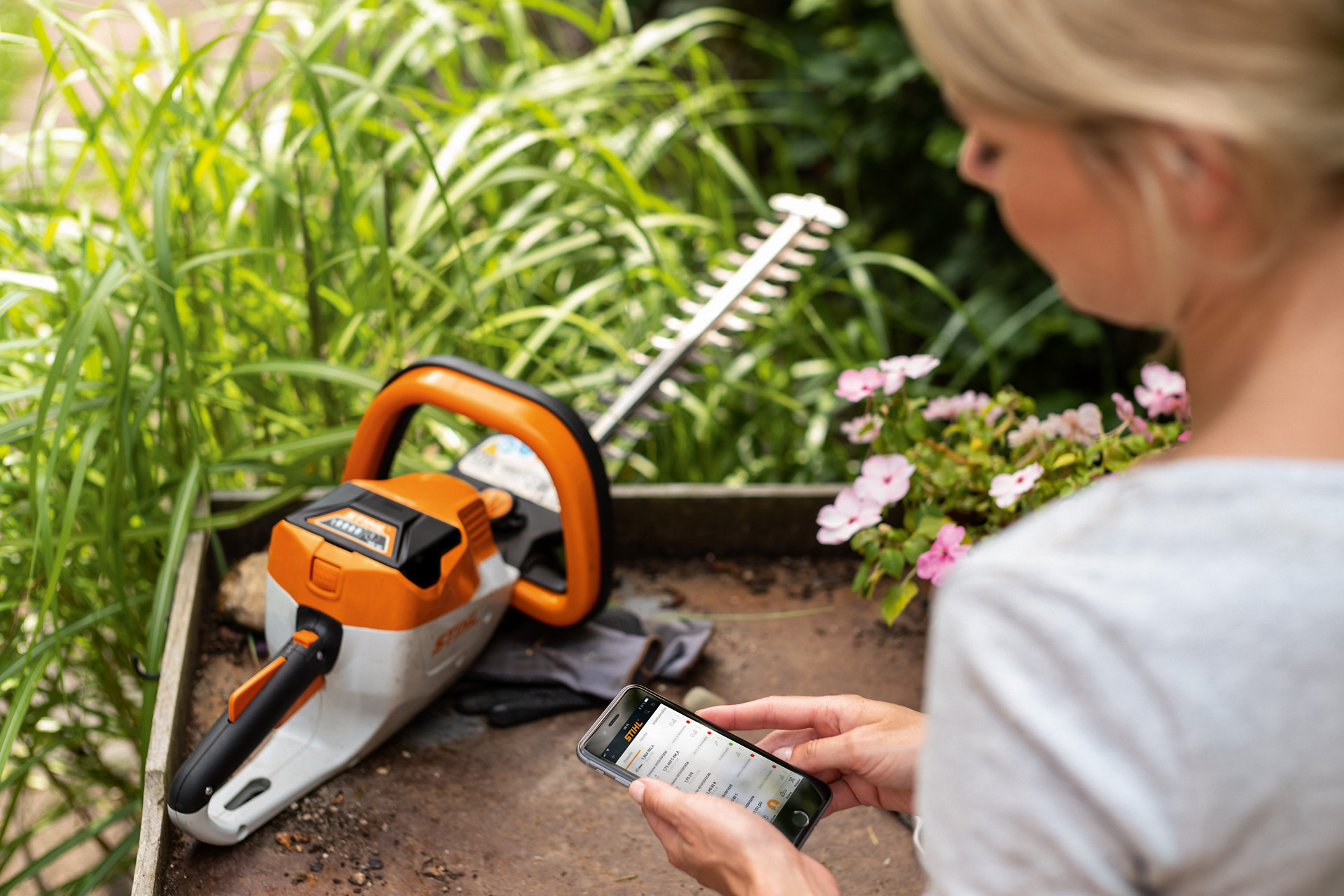 Une femme enregistre son taille-haie STIHL à l'aide de l'application STIHL sur son smartphone.