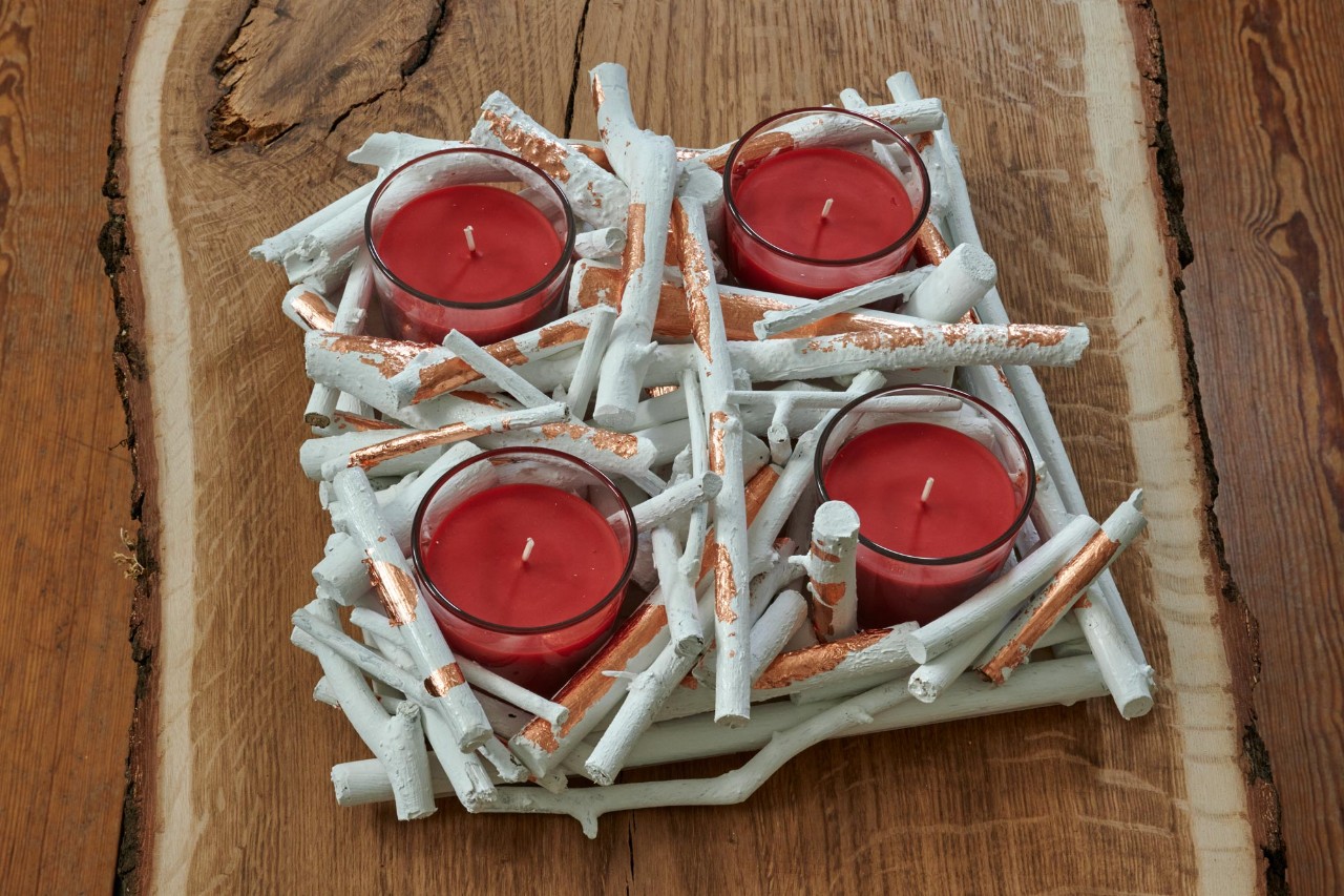 Couronne de l’Avent à fabriquer soi-même : une couronne de petites branches avec quatre bougies rouges dans des verres