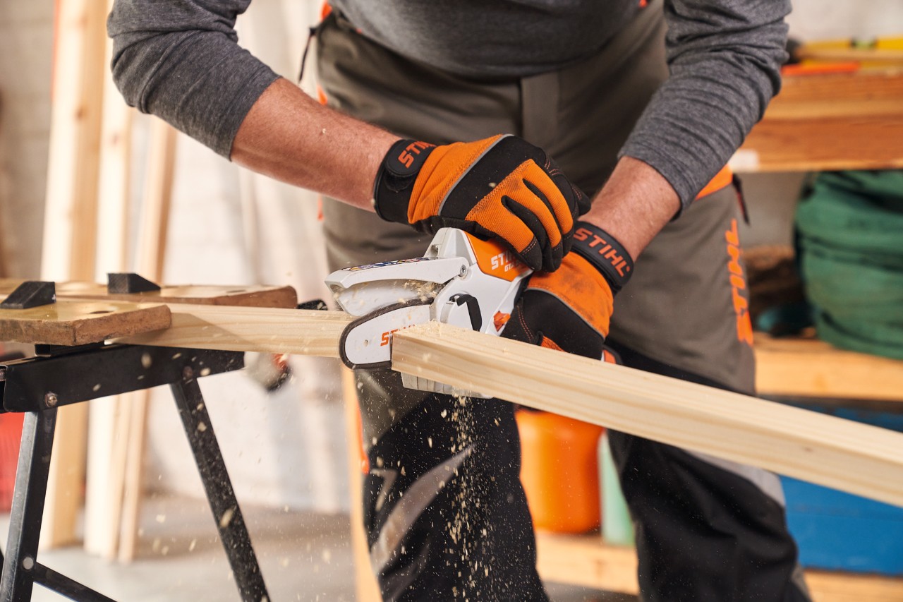 Personne avec gants STIHL Function&nbsp;Protect coupe des baguettes de cadre pour le brise-vue avec la scie de jardin STIHL&nbsp;GTA&nbsp;26