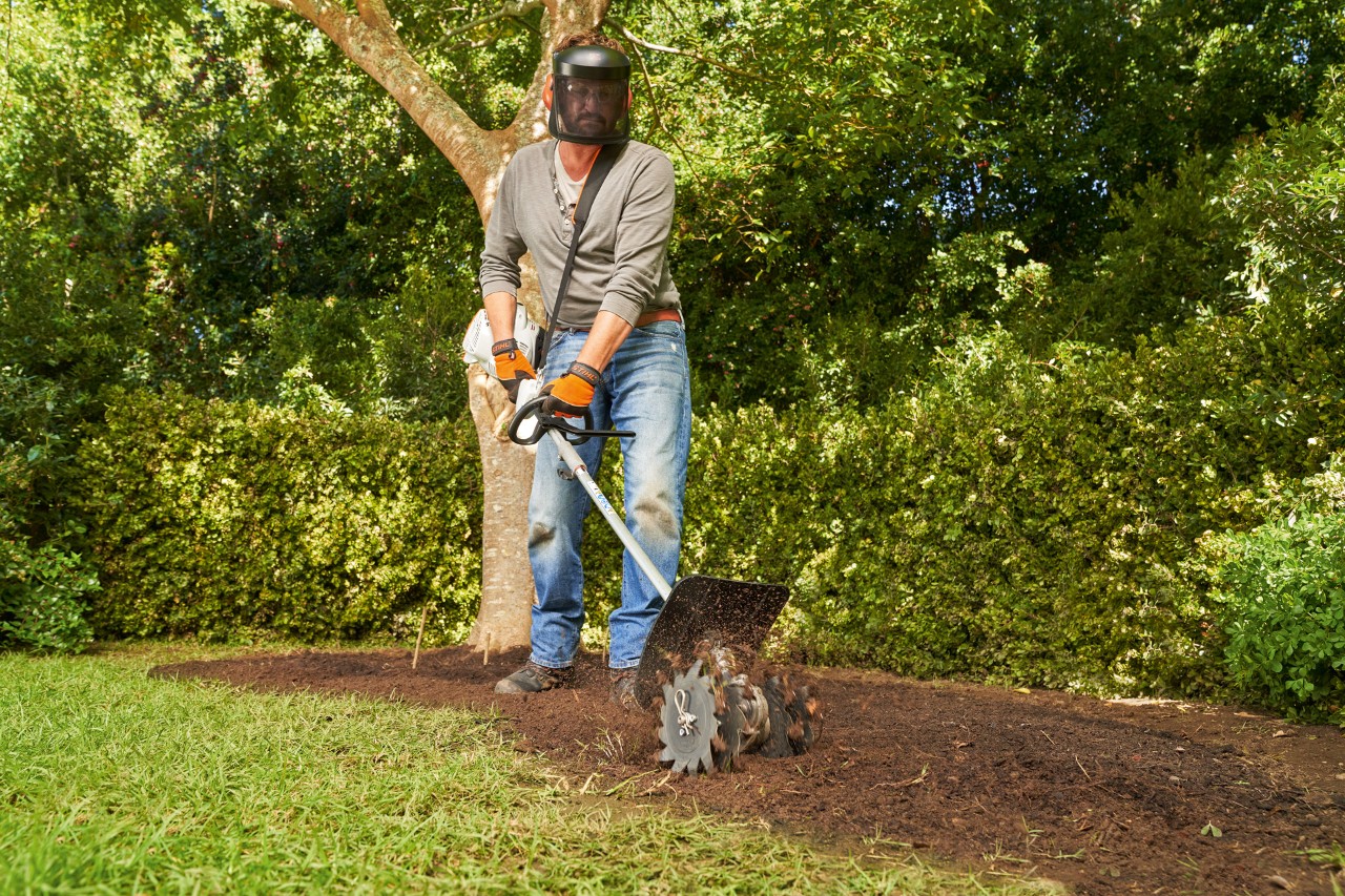 Avec un CombiSystème STIHL KM 56 RC-E, un homme intègre l’humus dans le sol