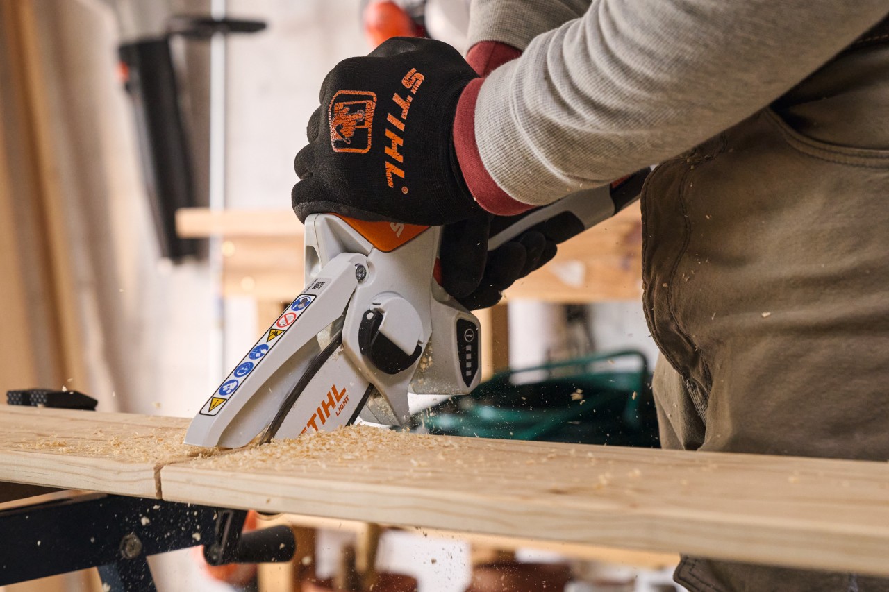 Un homme scie des planches de bois avec une scie de jardin à batterie STIHL GTA 26