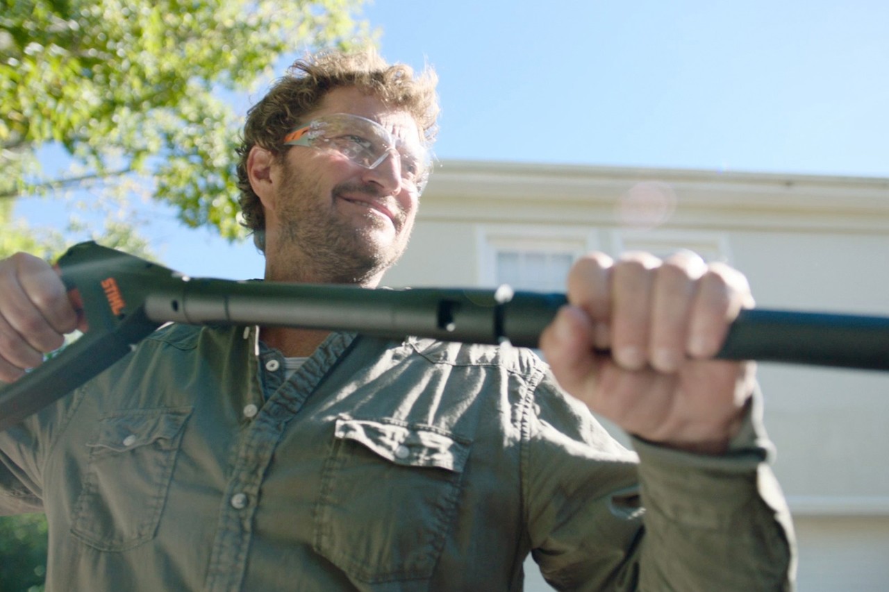 Un homme portant des lunettes de protection utilisant le nettoyeur haute pression STIHL RE 130 PLUS à l’extérieur