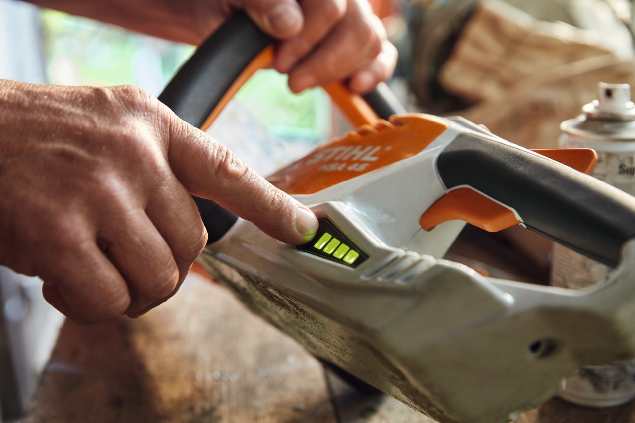 Iemand controleert de laadstatus van de STIHL HSA 45 accu-heggenschaar.