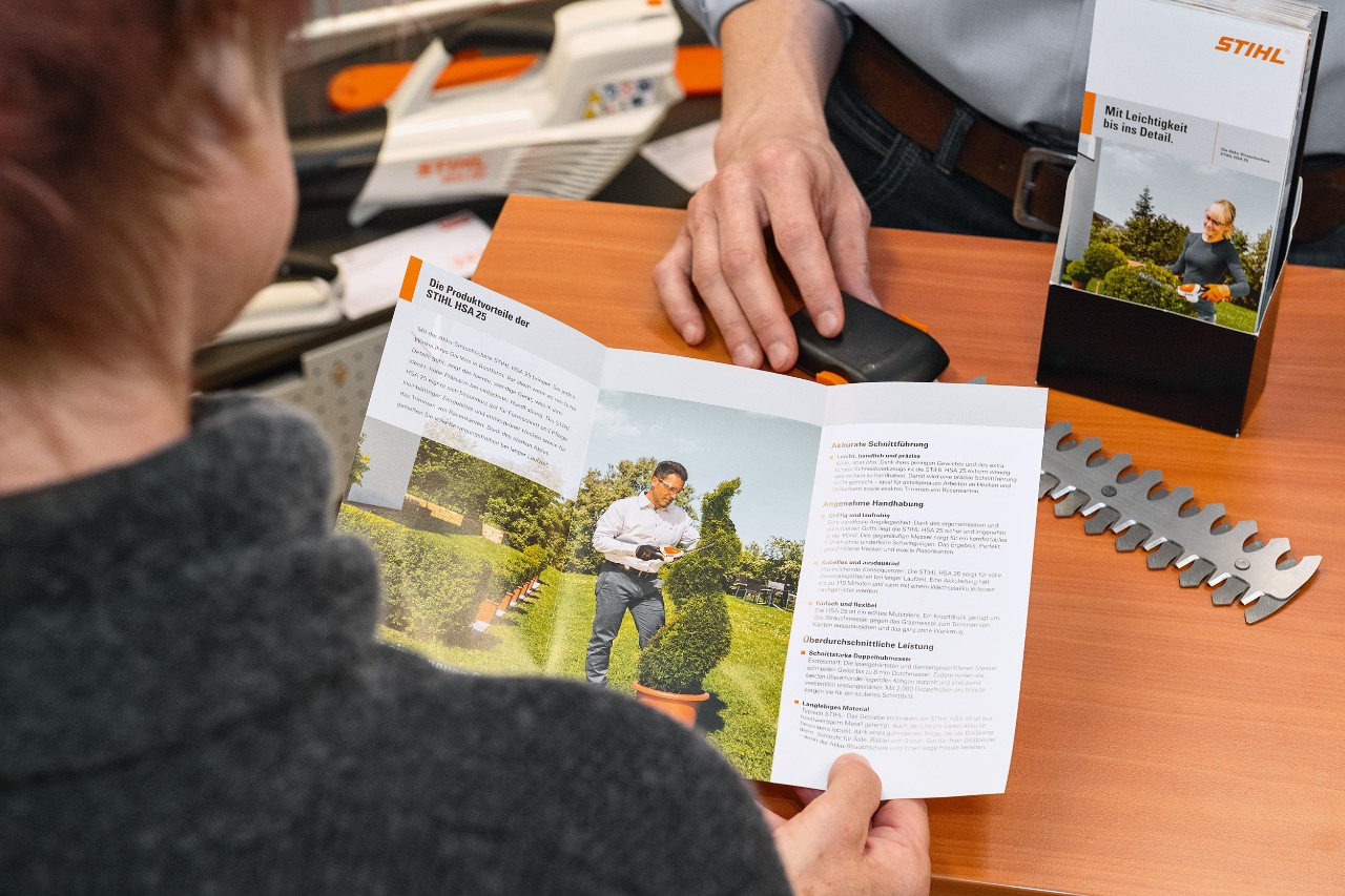 Iemand bekijkt de productvoordelen van de STIHL HSA 25 in een brochure